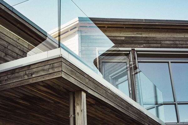 Parapetto in vetro su terrazza con facciata in legno