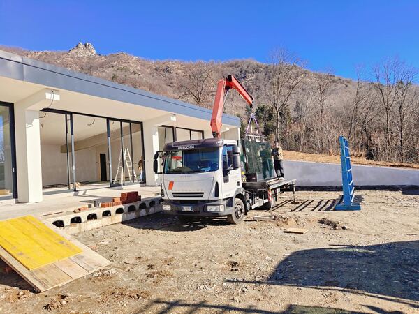 Consegna di vetrate isolanti a villa moderna con camion gru